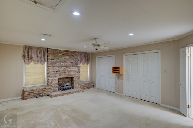 unfurnished living room with ceiling fan, carpet floors, crown molding, and a brick fireplace