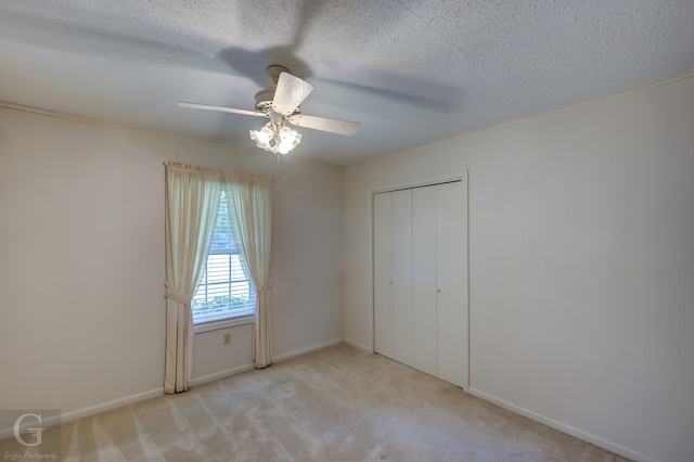 unfurnished bedroom featuring a textured ceiling, ceiling fan, a closet, and light carpet