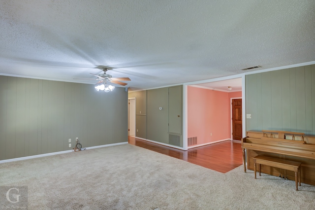 empty room with a textured ceiling, ceiling fan, ornamental molding, and carpet floors