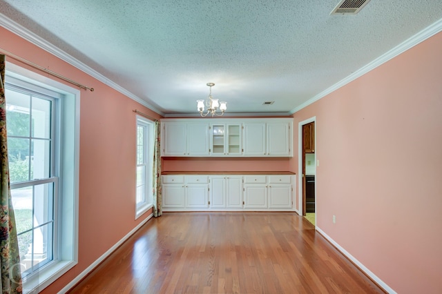 kitchen with a healthy amount of sunlight, visible vents, white cabinets, and a notable chandelier