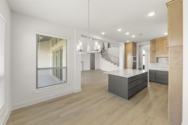 kitchen with light brown cabinets, hardwood / wood-style floors, a kitchen island, and hanging light fixtures