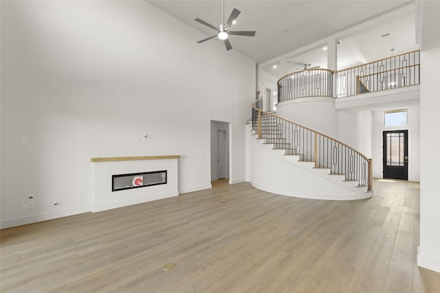 unfurnished living room with light wood-type flooring, high vaulted ceiling, and ceiling fan