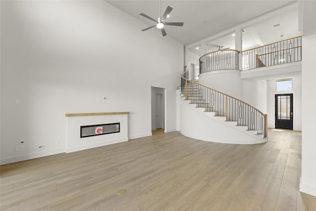 981 Stanford Ln, Prosper, TX 75078 - unfurnished living room with stairway, light wood-style flooring, a ceiling fan, and a high ceiling