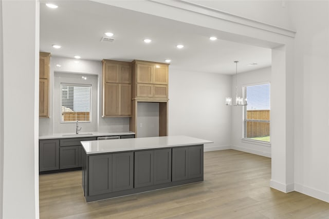 kitchen with a kitchen island, a notable chandelier, pendant lighting, and light wood-type flooring