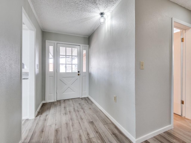 foyer with baseboards, a textured wall, a textured ceiling, and light wood finished floors