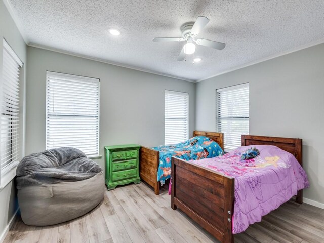 bedroom with ceiling fan, light hardwood / wood-style floors, and a textured ceiling