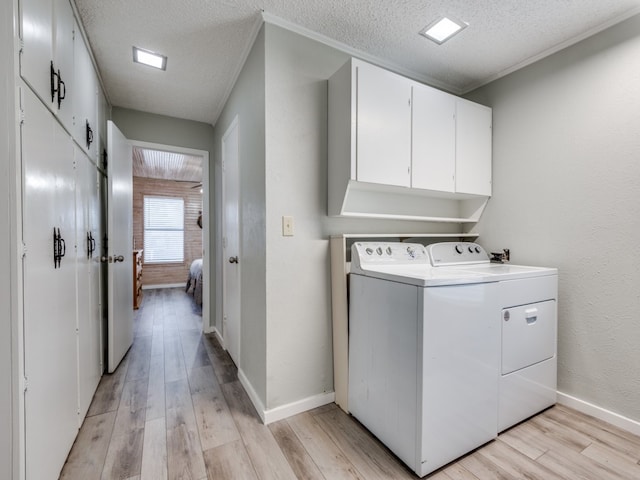 laundry room featuring a textured ceiling, light hardwood / wood-style flooring, cabinets, and washer and dryer