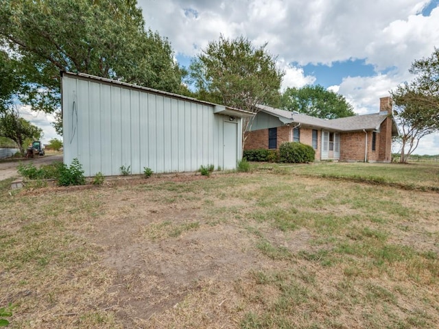 view of front facade featuring a front yard, a chimney, and brick siding