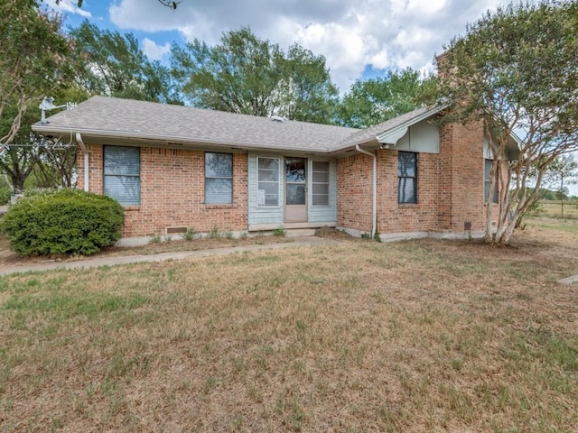 single story home featuring a shingled roof, a front yard, and brick siding