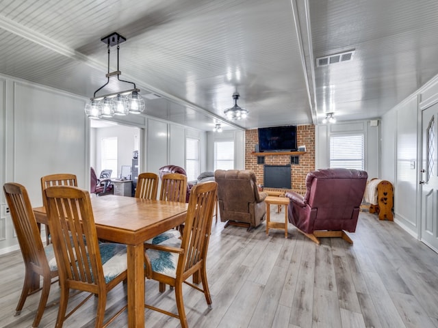 dining room featuring plenty of natural light, ceiling fan, light wood-type flooring, and a fireplace