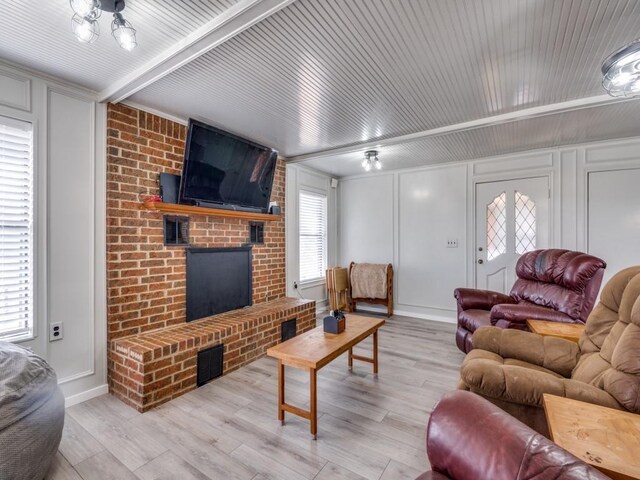 living room featuring a fireplace, brick wall, and light hardwood / wood-style flooring