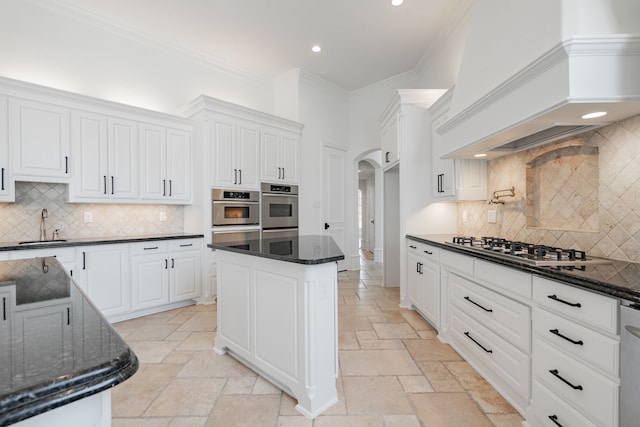 kitchen featuring stone tile floors, custom exhaust hood, arched walkways, and a sink