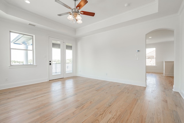 empty room featuring crown molding, ceiling fan, a raised ceiling, and light wood-type flooring