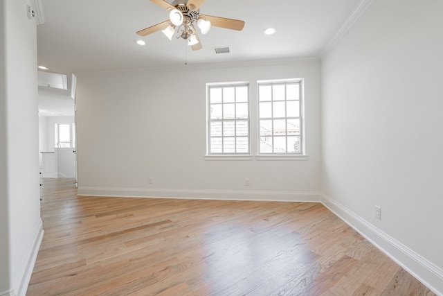 spare room featuring crown molding, baseboards, visible vents, and light wood-style floors