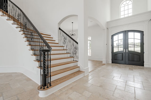 entrance foyer with stone tile flooring, baseboards, french doors, and a high ceiling