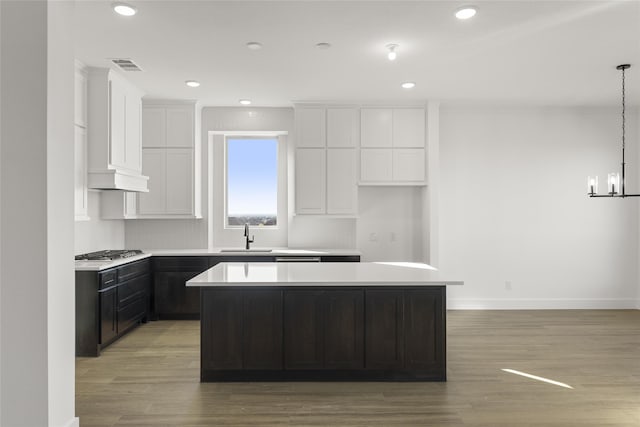 kitchen with light wood-type flooring, a kitchen island, stainless steel gas stovetop, and sink