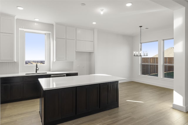 kitchen featuring decorative light fixtures, a center island, sink, and light hardwood / wood-style flooring