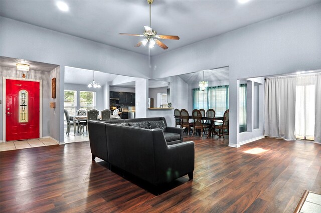 tiled living room featuring ceiling fan with notable chandelier and a towering ceiling