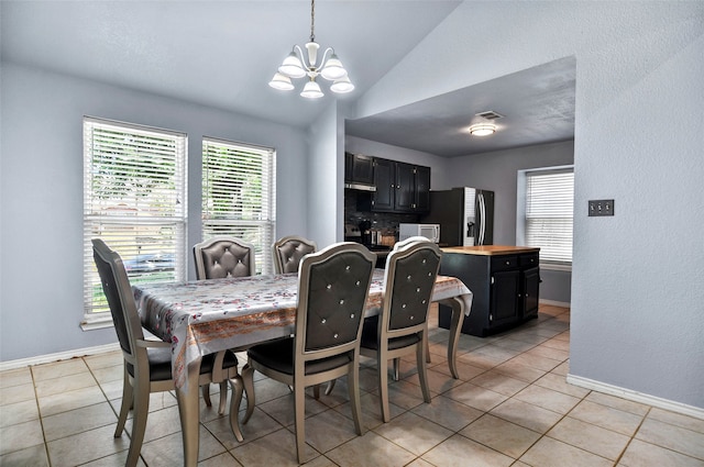 dining space featuring lofted ceiling, light tile patterned floors, and a chandelier