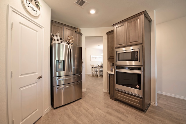 kitchen with appliances with stainless steel finishes and light hardwood / wood-style flooring