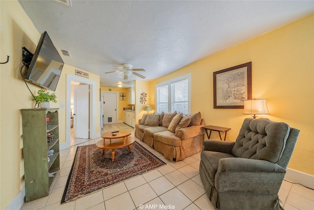 living area featuring light tile patterned floors, visible vents, baseboards, a ceiling fan, and a textured ceiling