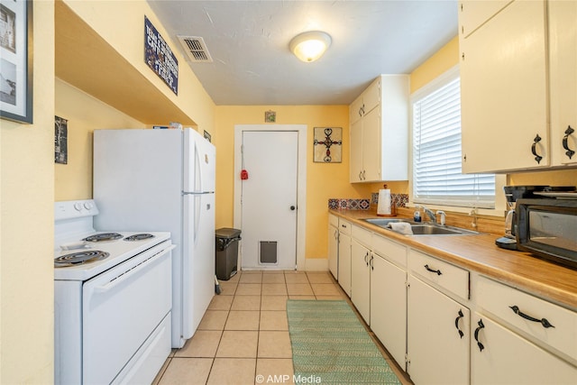 kitchen with white electric stove, light tile patterned floors, a sink, visible vents, and light countertops