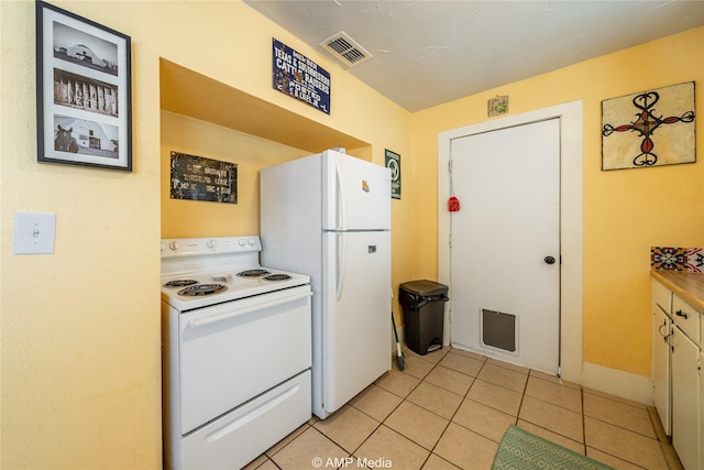 kitchen with light tile patterned floors, light countertops, white appliances, and visible vents