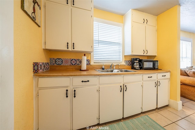 kitchen with white cabinetry, light countertops, a sink, and light tile patterned flooring