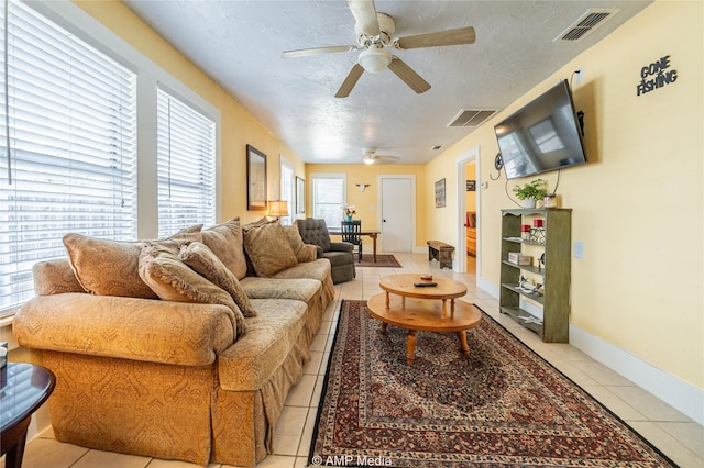 living room with visible vents, a textured ceiling, baseboards, and light tile patterned floors