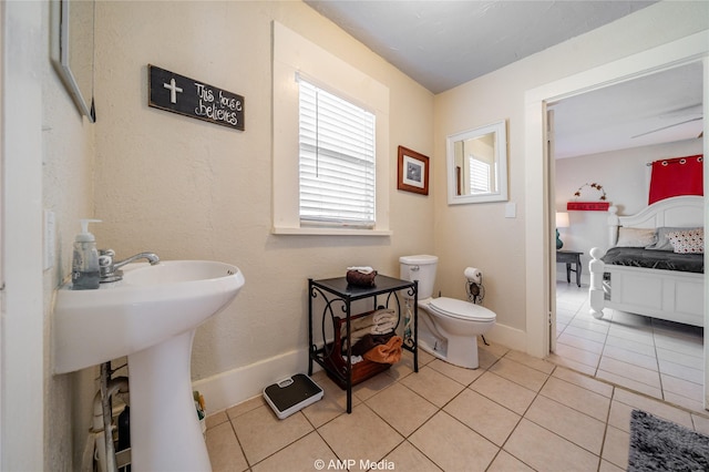 half bath featuring baseboards, toilet, and tile patterned floors