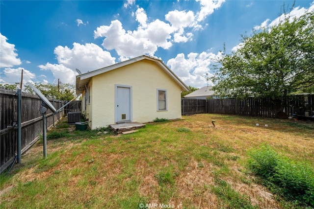 back of property featuring cooling unit, a fenced backyard, a yard, and stucco siding