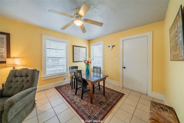 dining space with light tile patterned floors, a textured ceiling, a ceiling fan, and baseboards