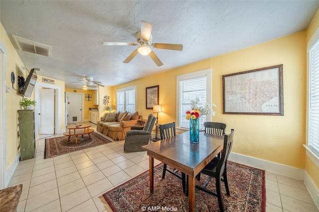 dining space with light tile patterned floors, visible vents, ceiling fan, a textured ceiling, and baseboards