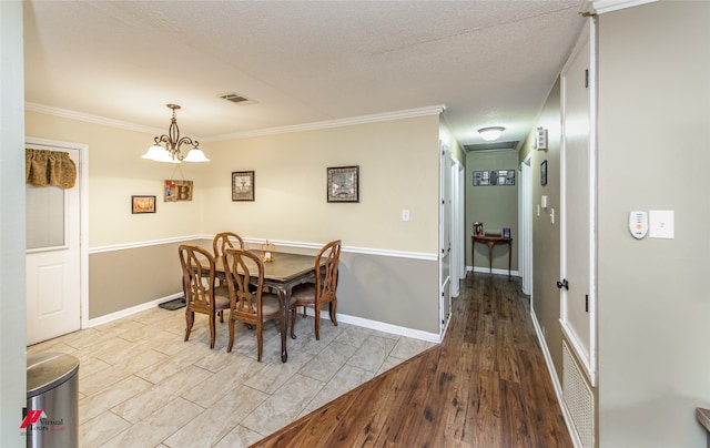 dining room featuring an inviting chandelier, crown molding, a textured ceiling, and light hardwood / wood-style floors