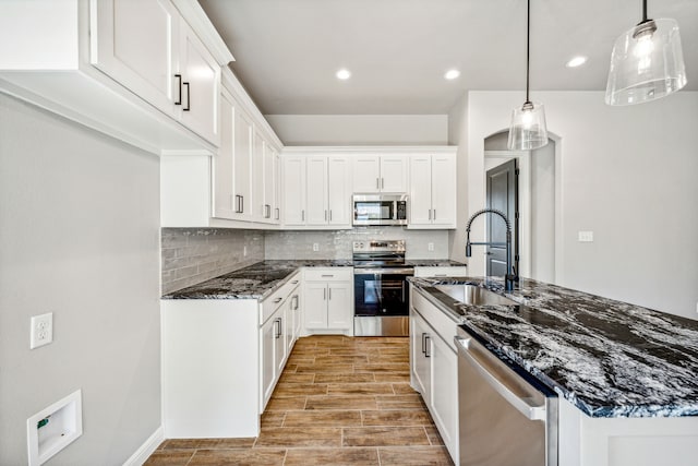 kitchen featuring appliances with stainless steel finishes, decorative backsplash, white cabinetry, and hanging light fixtures