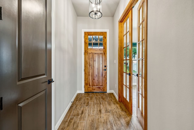 doorway to outside featuring a chandelier and light hardwood / wood-style floors