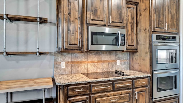 kitchen with stainless steel appliances, light stone counters, dark brown cabinetry, and backsplash