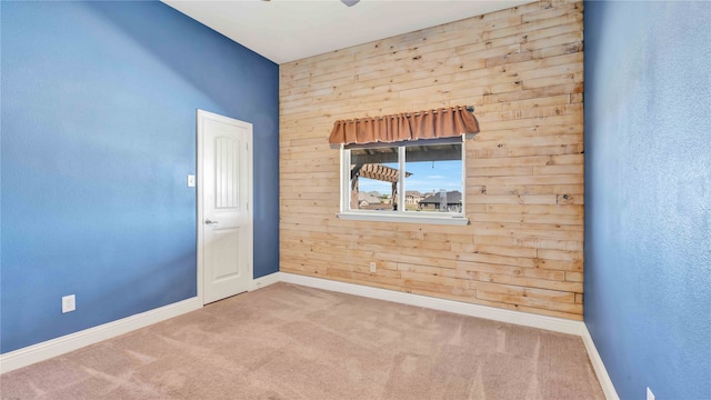 spare room featuring carpet floors and wood walls