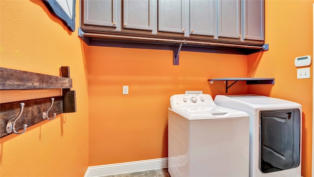 clothes washing area featuring cabinets and washer and clothes dryer