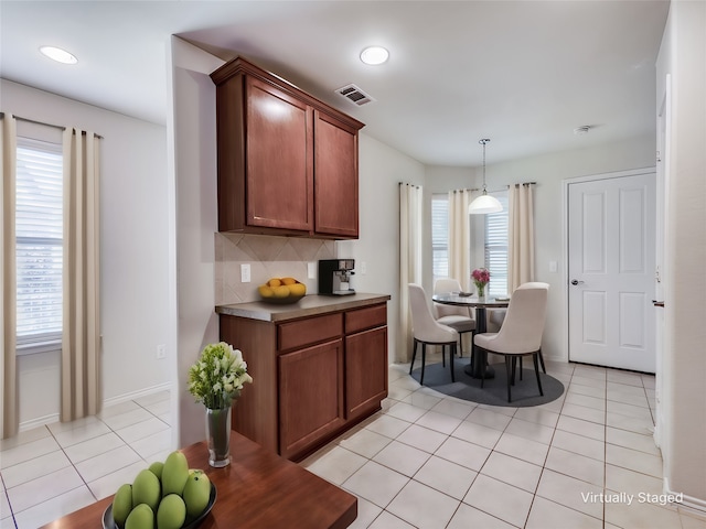 kitchen with decorative backsplash, decorative light fixtures, light tile patterned flooring, and a healthy amount of sunlight