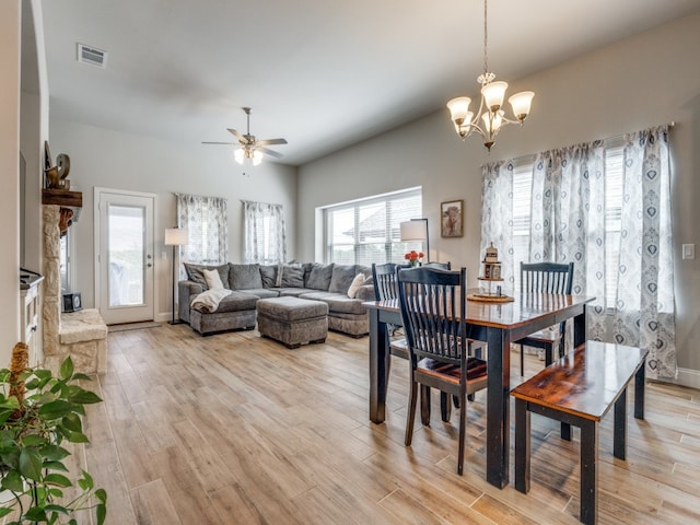 dining area with a fireplace, light hardwood / wood-style flooring, and ceiling fan with notable chandelier