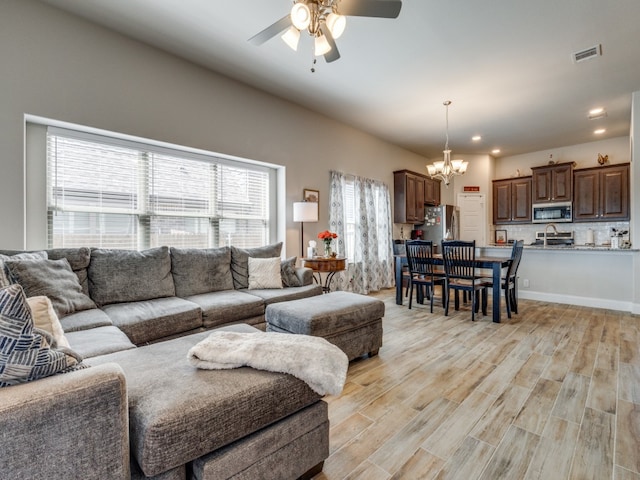 living room featuring sink, ceiling fan with notable chandelier, and light wood-type flooring