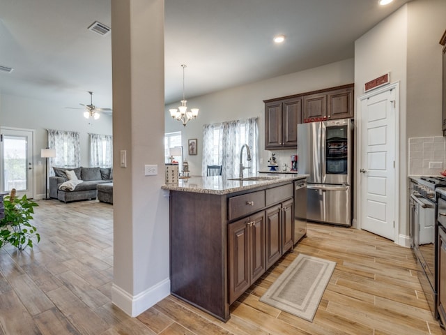 kitchen with sink, ceiling fan with notable chandelier, stainless steel appliances, and dark brown cabinets