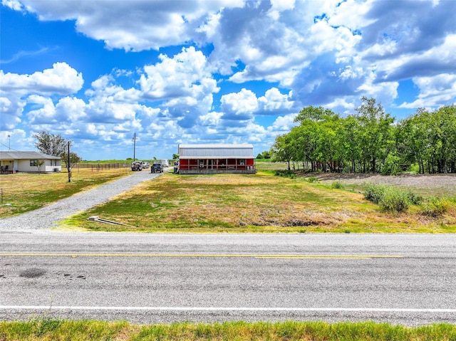 view of front of property featuring an outbuilding, a rural view, driveway, and a front yard