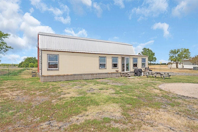 back of house with entry steps, metal roof, and a lawn