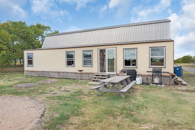 back of house featuring entry steps, metal roof, and a lawn