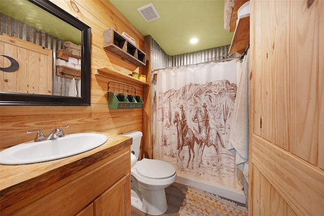 bathroom with wood walls, a shower with curtain, toilet, and vanity