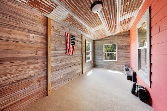 carpeted empty room featuring lofted ceiling, wooden ceiling, and wood walls