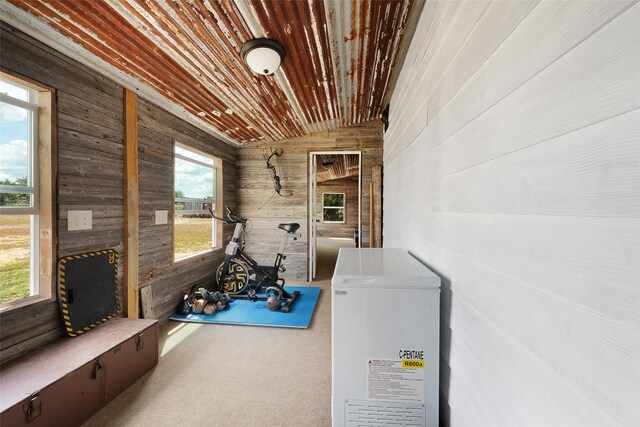 exercise room featuring wood ceiling and wooden walls