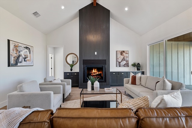 living room with light hardwood / wood-style flooring, high vaulted ceiling, and a fireplace